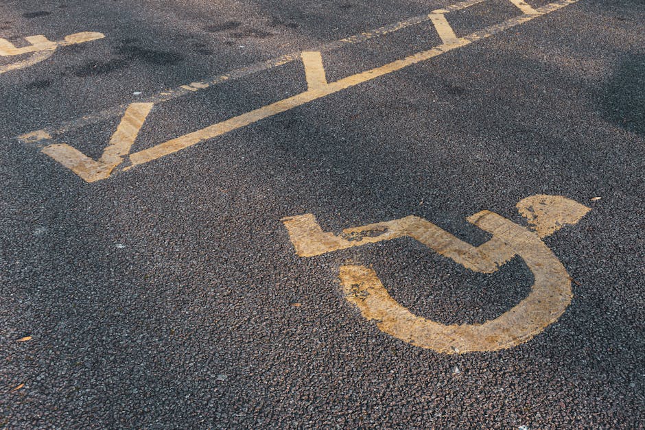 A blue and white parking sign indicating accessible parking with a wheelchair symbol and arrows pointing left and right, mounted on a metal pole in front of a textured brick wall. The wall is composed of rectangular bricks in shades of grey, with some bricks protruding slightly to create a pattern. The scene is evenly lit by natural daylight, with no vehicles or additional objects visible, set in an outdoor environment likely near a building front or parking area. The signage and brickwork suggest a typical urban setting, and the context relates to parking or access regulations that may be relevant for waste removal or logistics services operating in the vicinity, such as those provided by Rubbish Clearance Fulham.